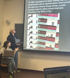 Students presenting in front of a slide showing a John Portman building